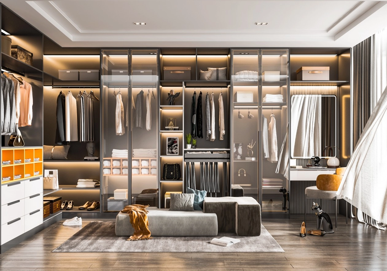 Spacious walk-in closet with glass-front cabinets, warm lighting, and a gray lounge area.
